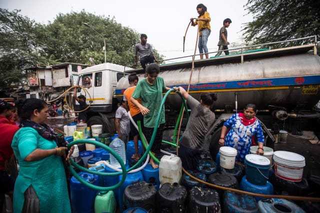 <p>Residents use hoses to collect drinking water from a tanker truck in Delhi</p>