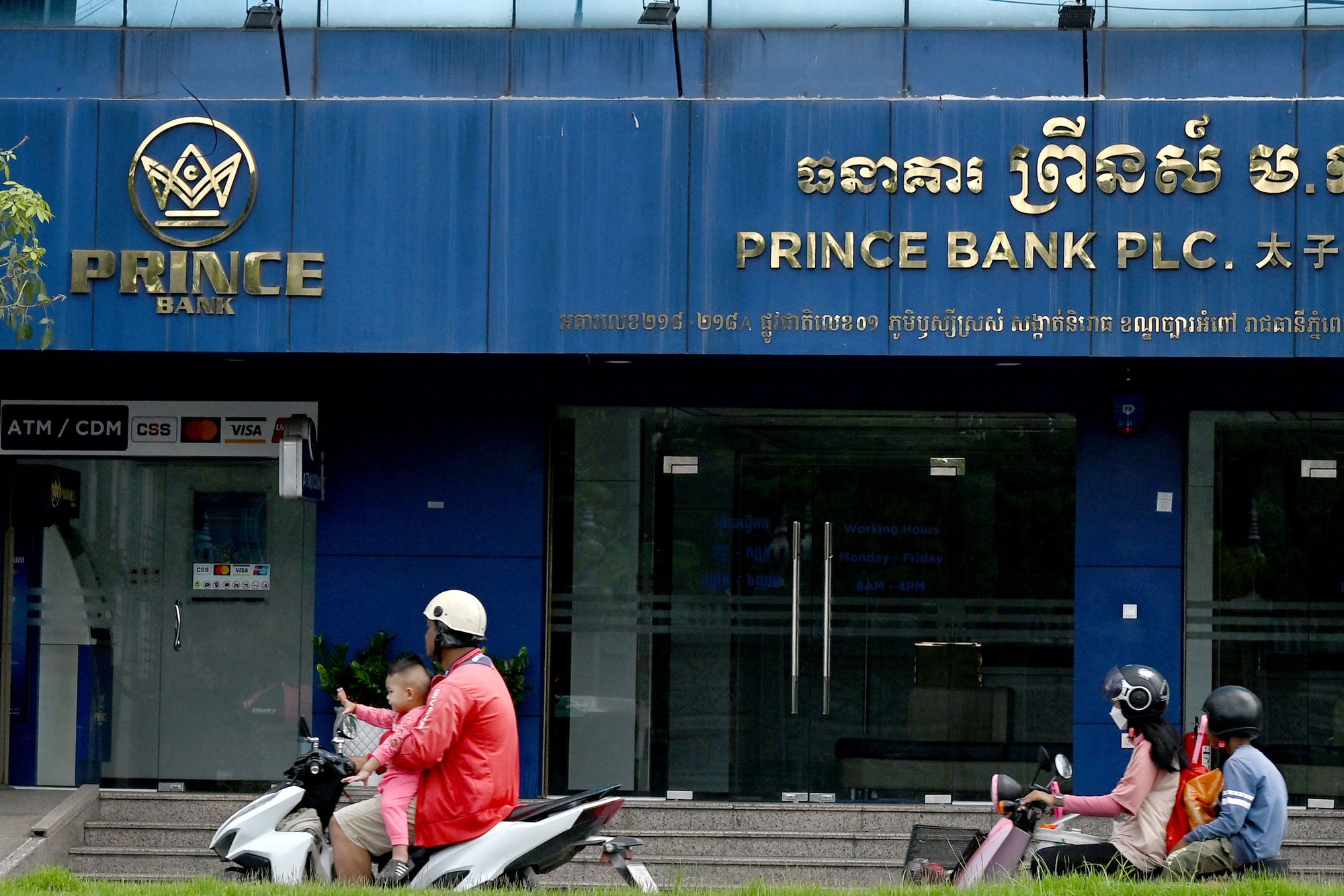 <p>File. Motorists ride past Prince Bank in Phnom Penh</p>