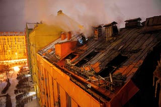 A rescue worker tries to put out a fire at a residential building damaged after a Russian strike on Kyiv