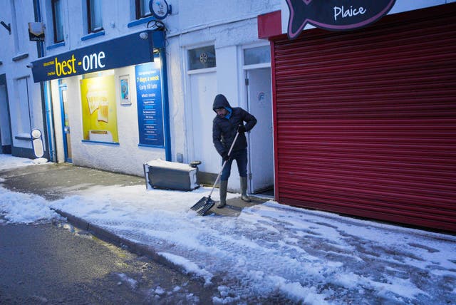 <p>A man clears snow from a pavement in  Dowlais during Storm Goretti</p>