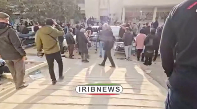 <p>Mourners move between the dead who are laid out inside several warehouses and even along an internal road in Tehran</p>