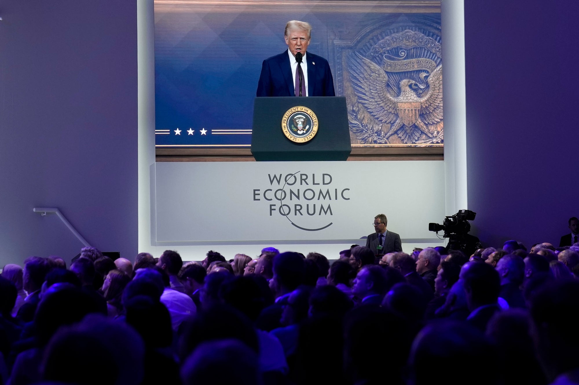 Attendees listen to a virtual speech delivered by U.S. president Donald Trump in 2025.