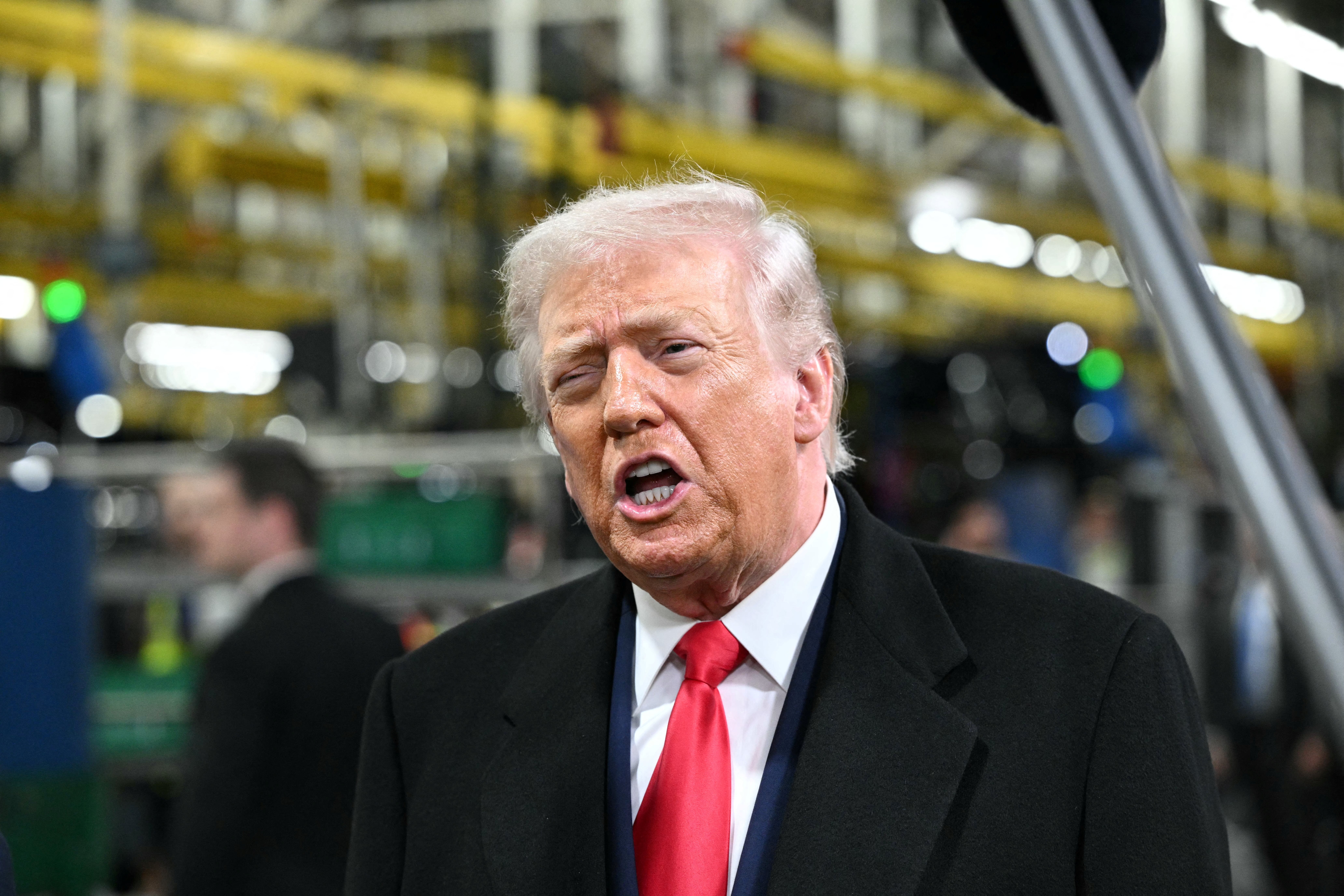 Donald Trump appeared to mouth an expletive and stick up his middle finger after being heckled at an automotive plant in Michigan
