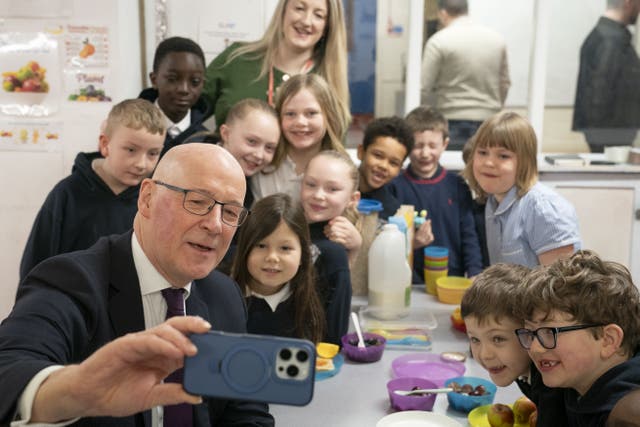 First Minister John Swinney highlighted the support for families the Budget offers as he visited a primary school breakfast club (Jane Barlow/PA)
