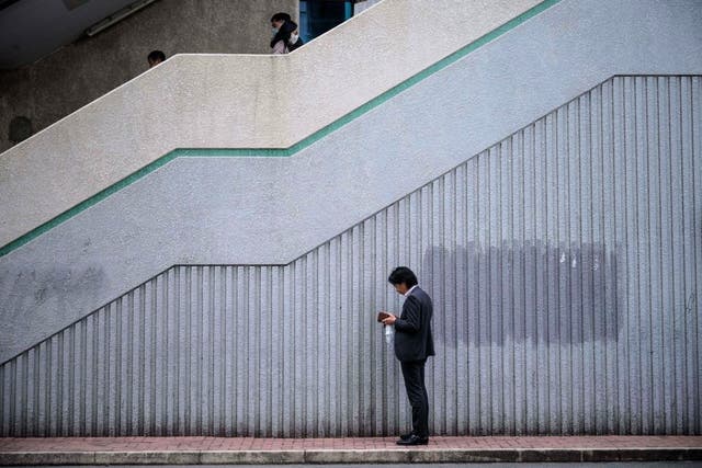 <p>A man checks his phone on a pavement in Hong Kong on 4 January, 2021</p>