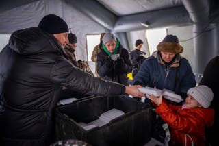 Os residentes recebem comida gratuita num centro de emergência criado durante cortes de energia causados ​​pelos ataques aéreos regulares da Rússia contra os centros energéticos do país em Boryspil, na Ucrânia.