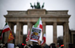 A demonstrator displays a placard calling for the return of Reza Pahlavi, the son of Iran's late ruler Mohammad Reza Pahlavi during an anti-Iranian-government protest in front of the Brandenburg Gate in Berlin, Germany, on 12 January 2026