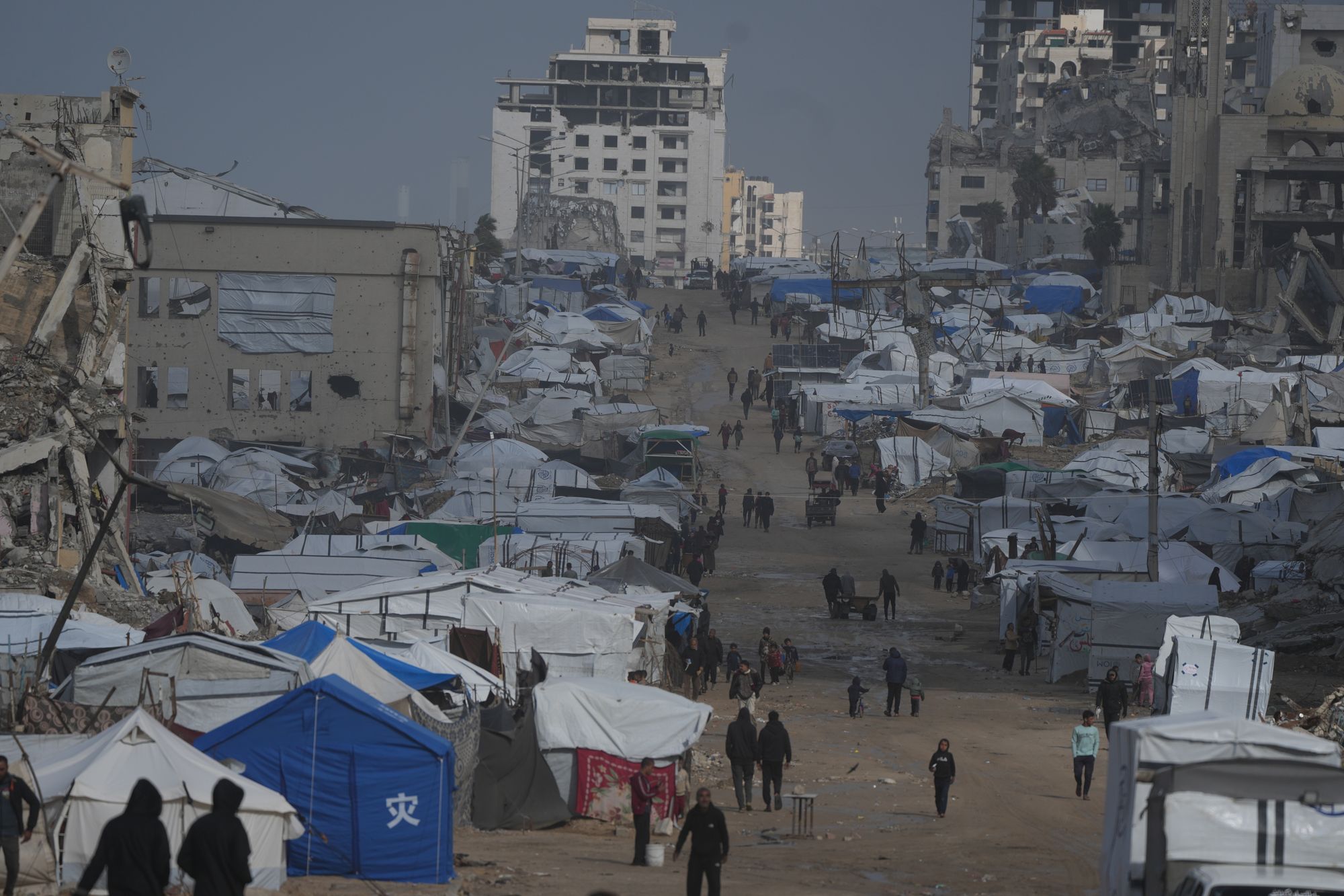 Palestinians walk along a street lined with damaged buildings in Gaza City