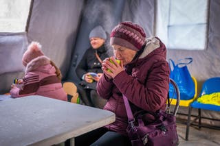 A woman gets warm with a hot cup of tea at an emergency centre in Boryspil on Wednesday