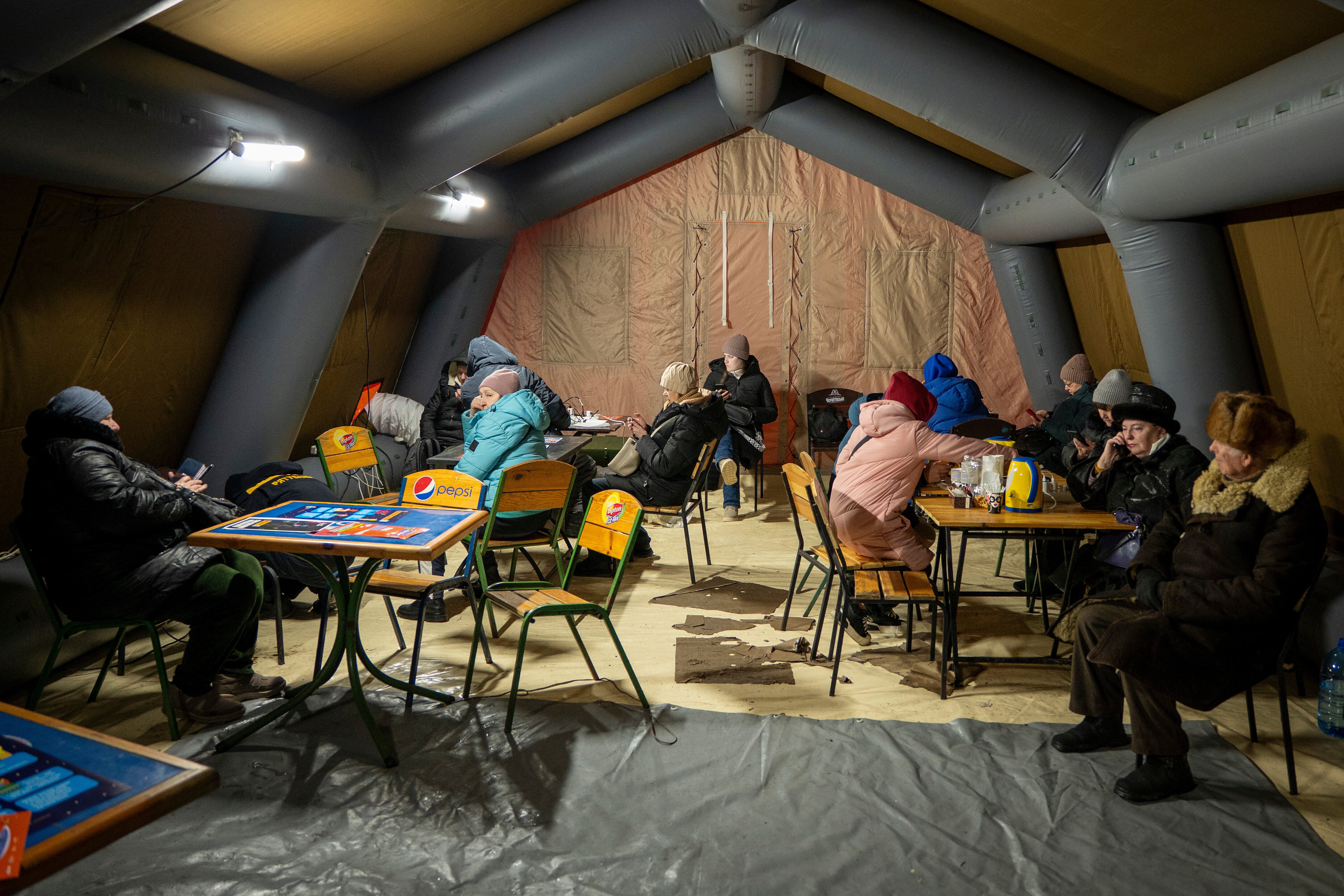 Ukrainians keep warm and charge their devices in a tent set up by the emergency service following Russia's regular air attacks on Kyiv