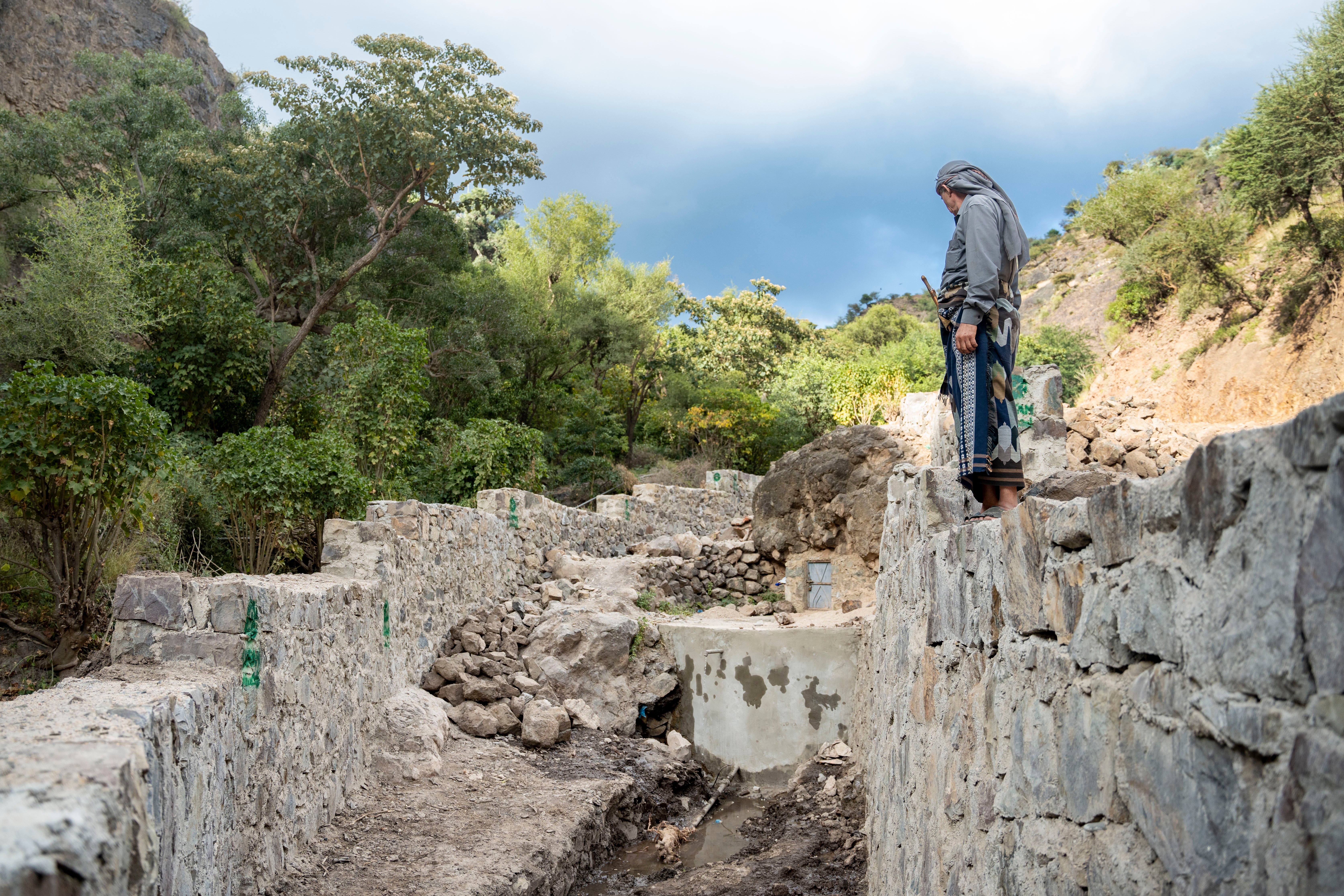 55-year-old Jameel Mahyoub Saif, is pictured next to water infrastructure that has been rehabilitated with concrete in his village