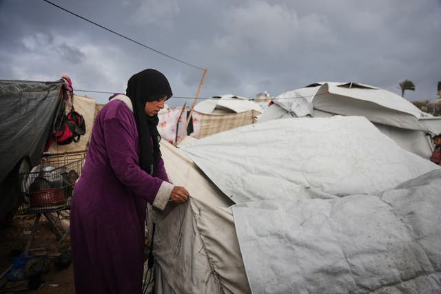 <p>A woman fixes her makeshift tent in Zawaida, central Gaza</p>