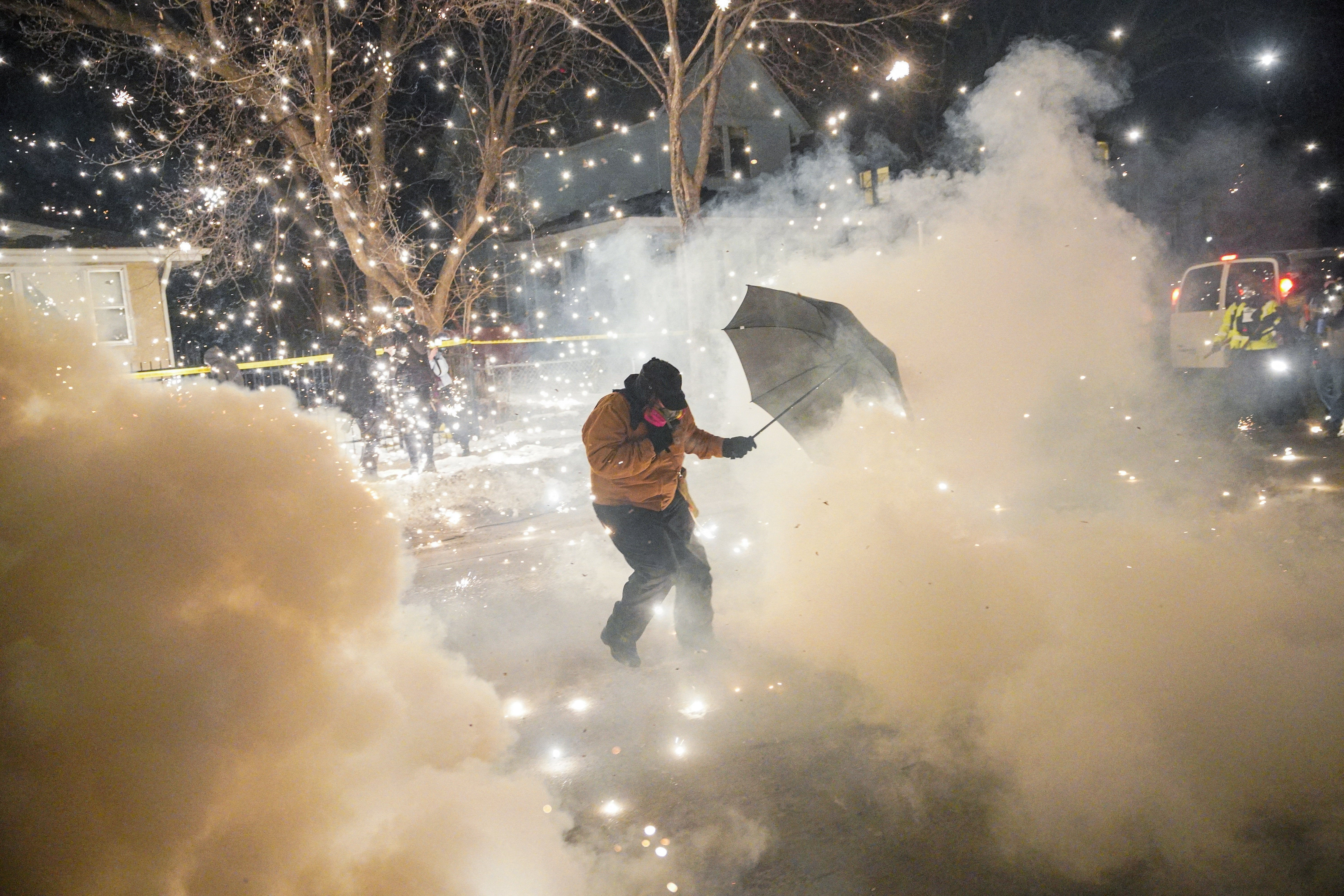 A protesting community member attempts to protect themselves as federal agents fire munitions and pepper balls, as tensions rise after federal law enforcement agents were involved in a shooting incident, a week after a U.S. Immigration and Customs Enforcement (ICE) agent fatally shot Renee Nicole Good, in north Minneapolis, Minnesota, U.S., January 14, 2026