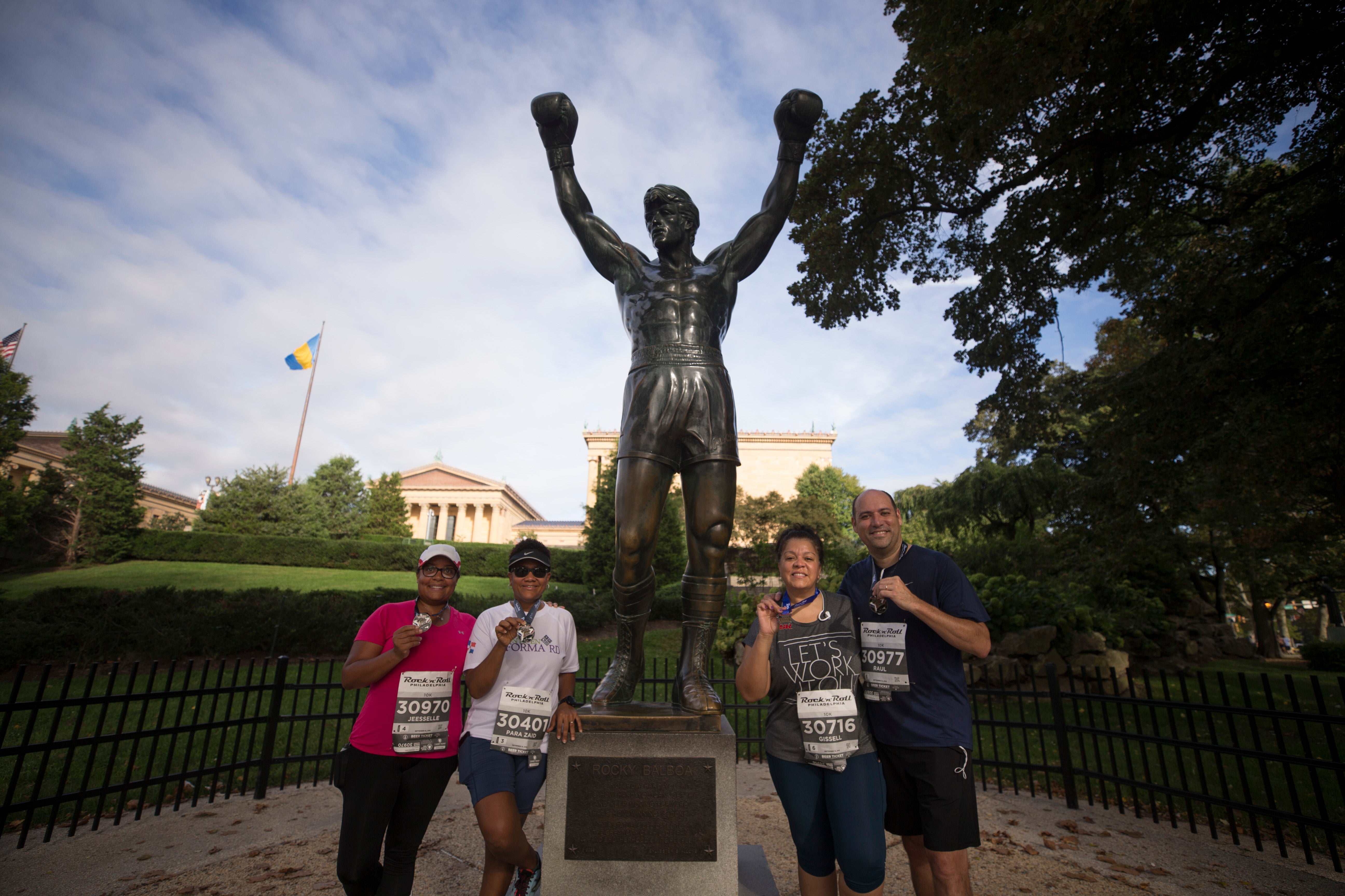 Corredores posam para uma foto em frente à estátua de Rocky em 2018. A estátua será movida para o topo das escadas do lado de fora do Museu de Arte da Filadélfia ainda este ano.