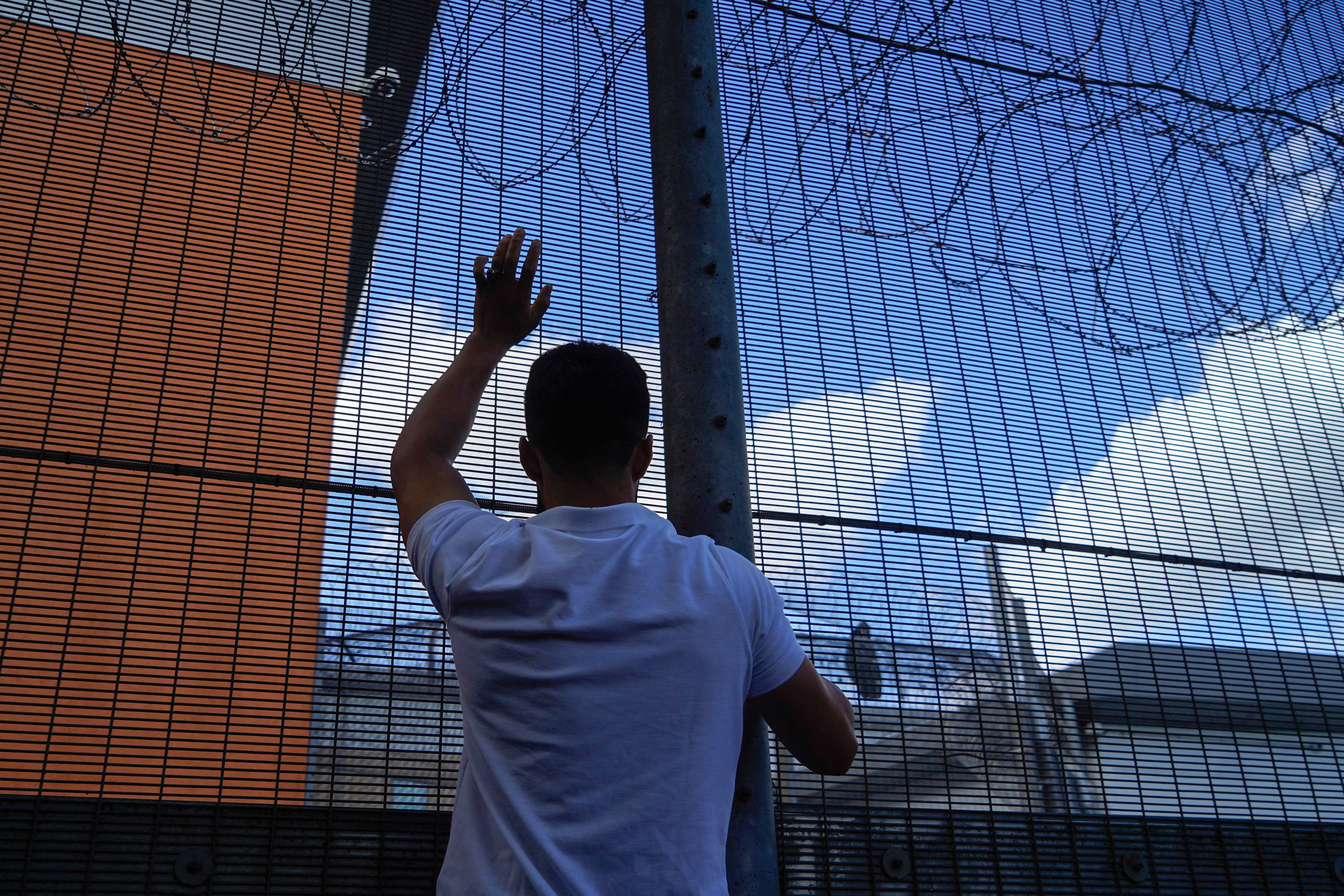 A protester communicates with those inside at the perimeter fence of Brook House immigration removal centre beside Gatwick Airport, south of London in 2022