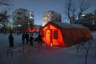 People leave and approach a tent provided by emergency services for residents whose apartments are left without heating during sub-zero temperatures