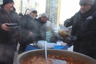 Chef Laert Arutiunian, partner of the World Central Kitchen, pours bohrach soup for people during a power blackout after critical civil infrastructure was hit by recent Russian missile and drone strikes, amid Russia's attack on Ukraine