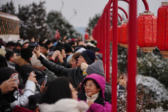 <p>People catch a sight of the snow-covered Forbidden City from a pavilion with lantern decorations at the Jingshan Park a day after the snow fall, in Beijing, Sunday, Jan. 18, 2026. (AP Photo/Andy Wong)</p>