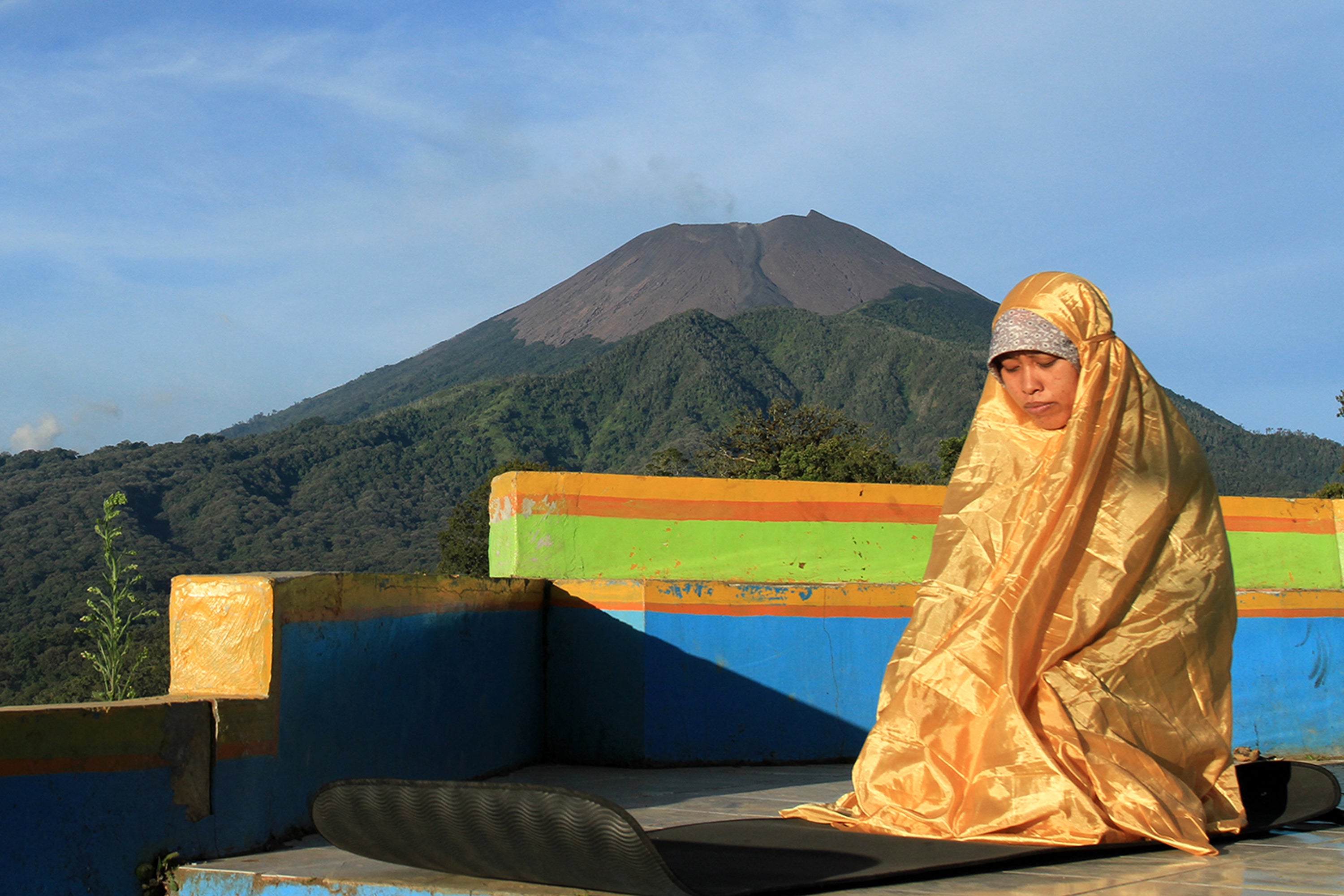 File. A woman prays in Brebes town in Indonesia's Java province with Mount Slamet in the background
