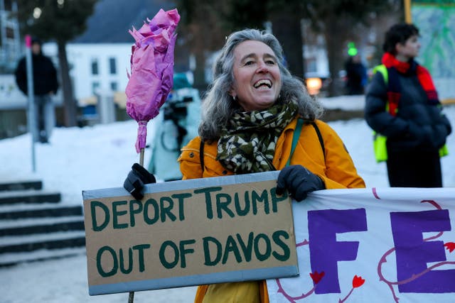 <p>An activist holds a placard with a slogan against U.S. President Donald Trump, during a protest, ahead of the opening of the World Economic Forum (WEF), in Davos, Switzerland</p>