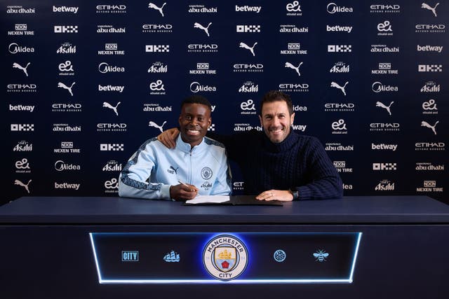 <p>Marc Guehi puts pen to paper alongside Manchester City’s director of football, Hugo Viana</p>