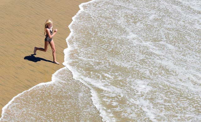 <p>A girls runs toward the water washing ashore at Huntington Beach in California on September 10, 2015, amid a heat wave where temperatures have reached triple digits in parts of southern California</p>