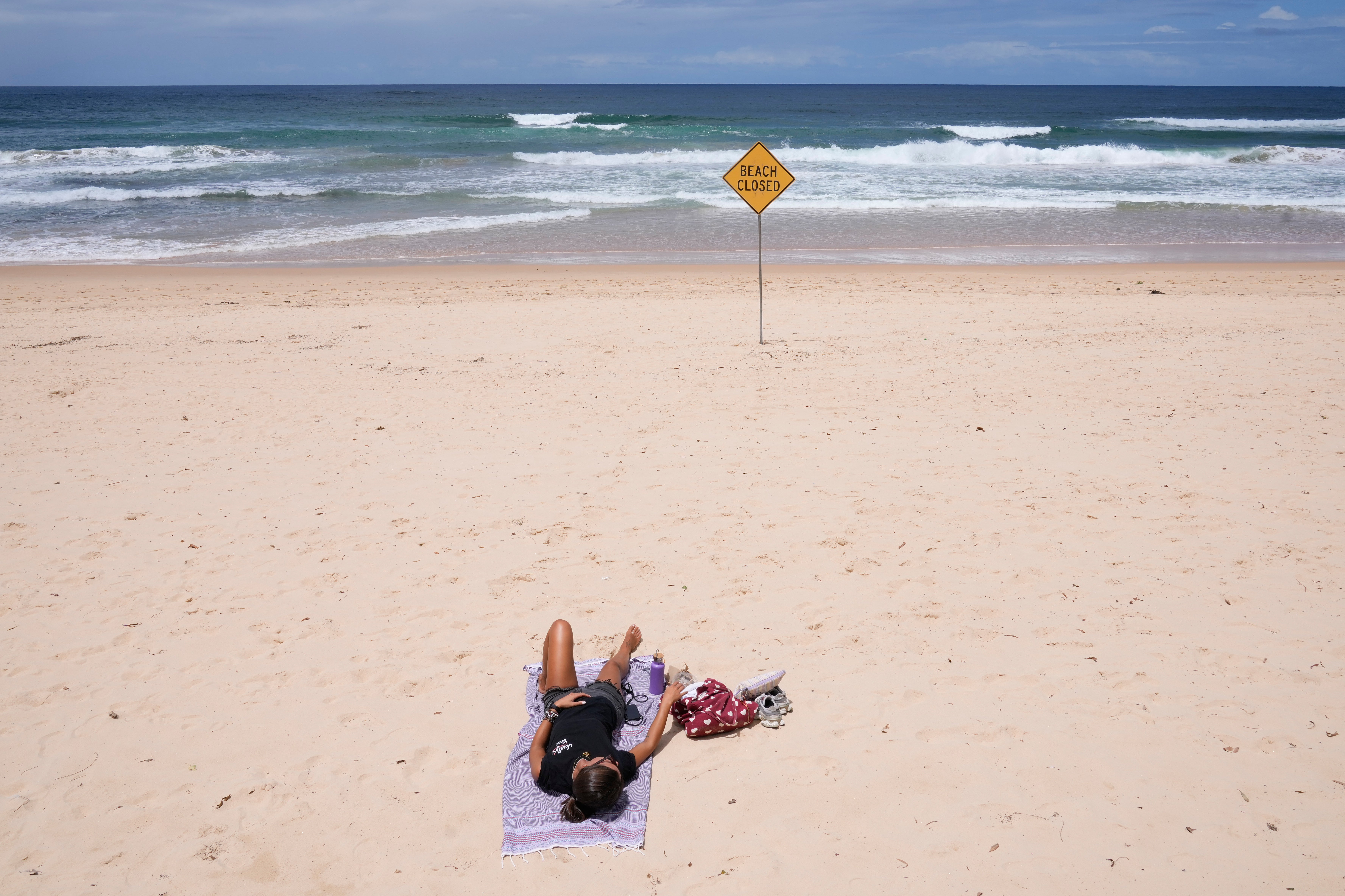 A lone sun bather relaxes at North Steyne Beach in Sydney after a series of shark attacks
