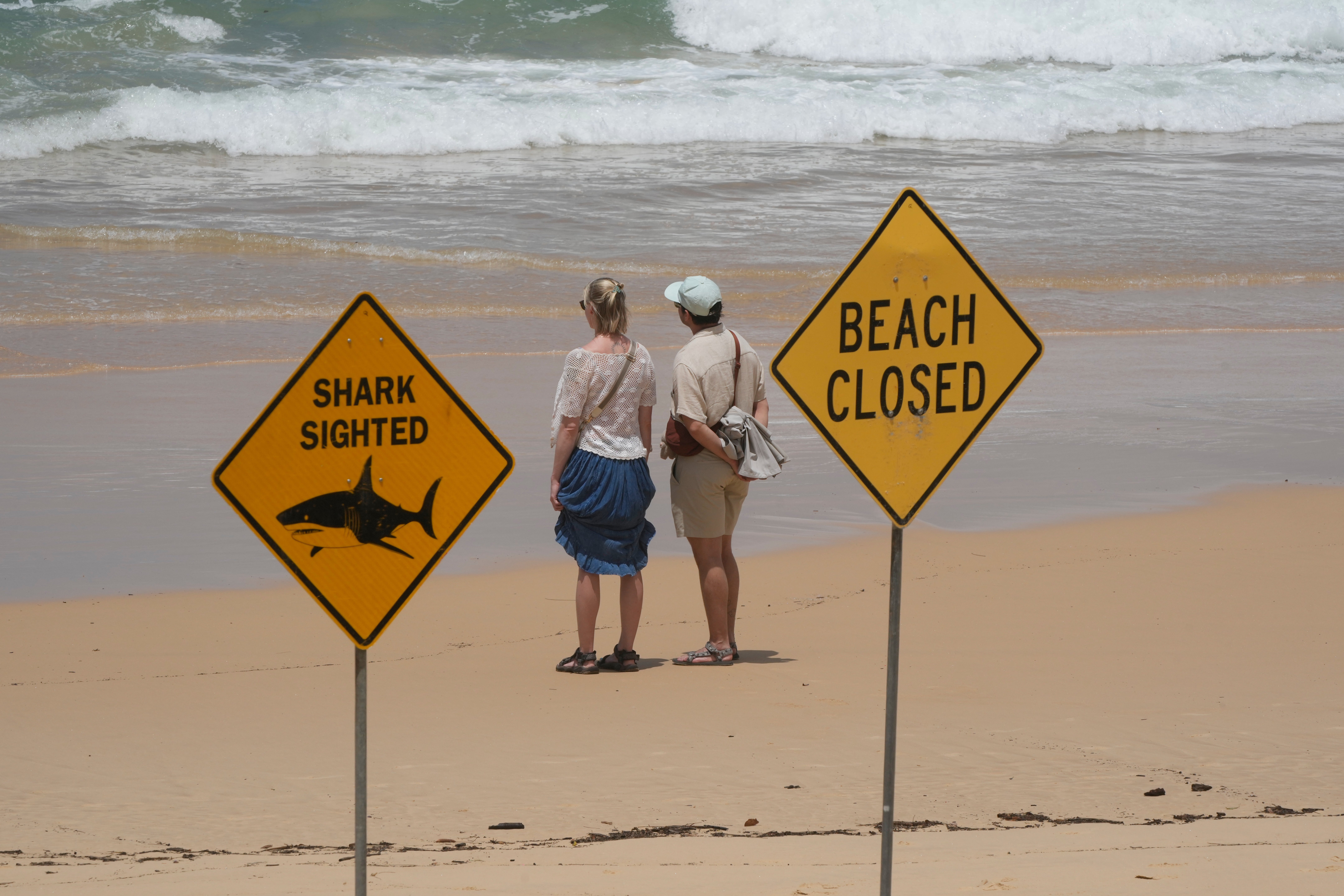 A couple look out to sea at North Steyne Beach in Sydney, Tuesday, Jan. 20, 2026, after a series of shark attacks. (AP Photo/Rick Rycroft)