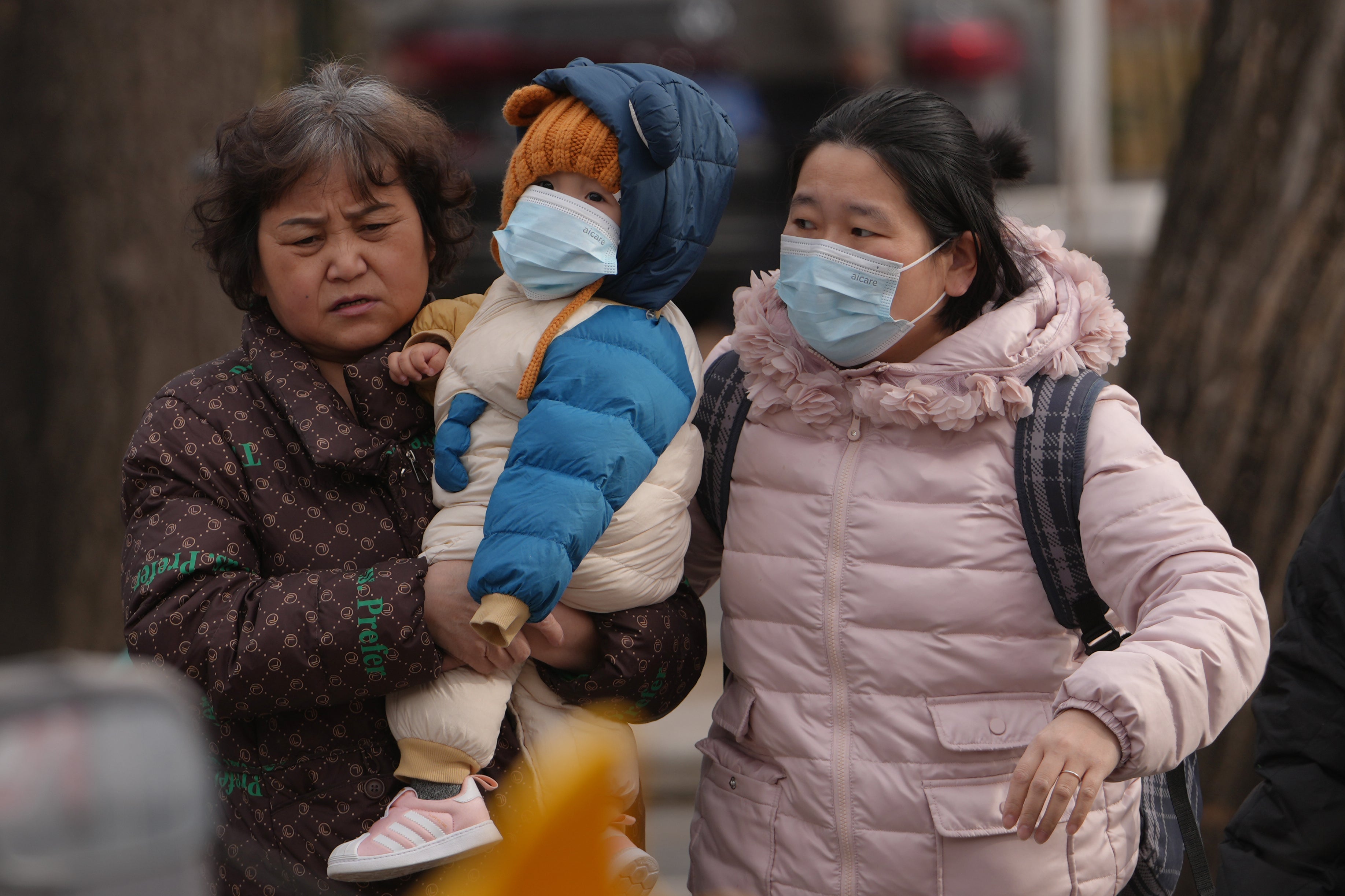 <p>Women carry a toddler across a street in Beijing, Monday, Jan. 19, 2026. (AP Photo/Andy Wong)</p>