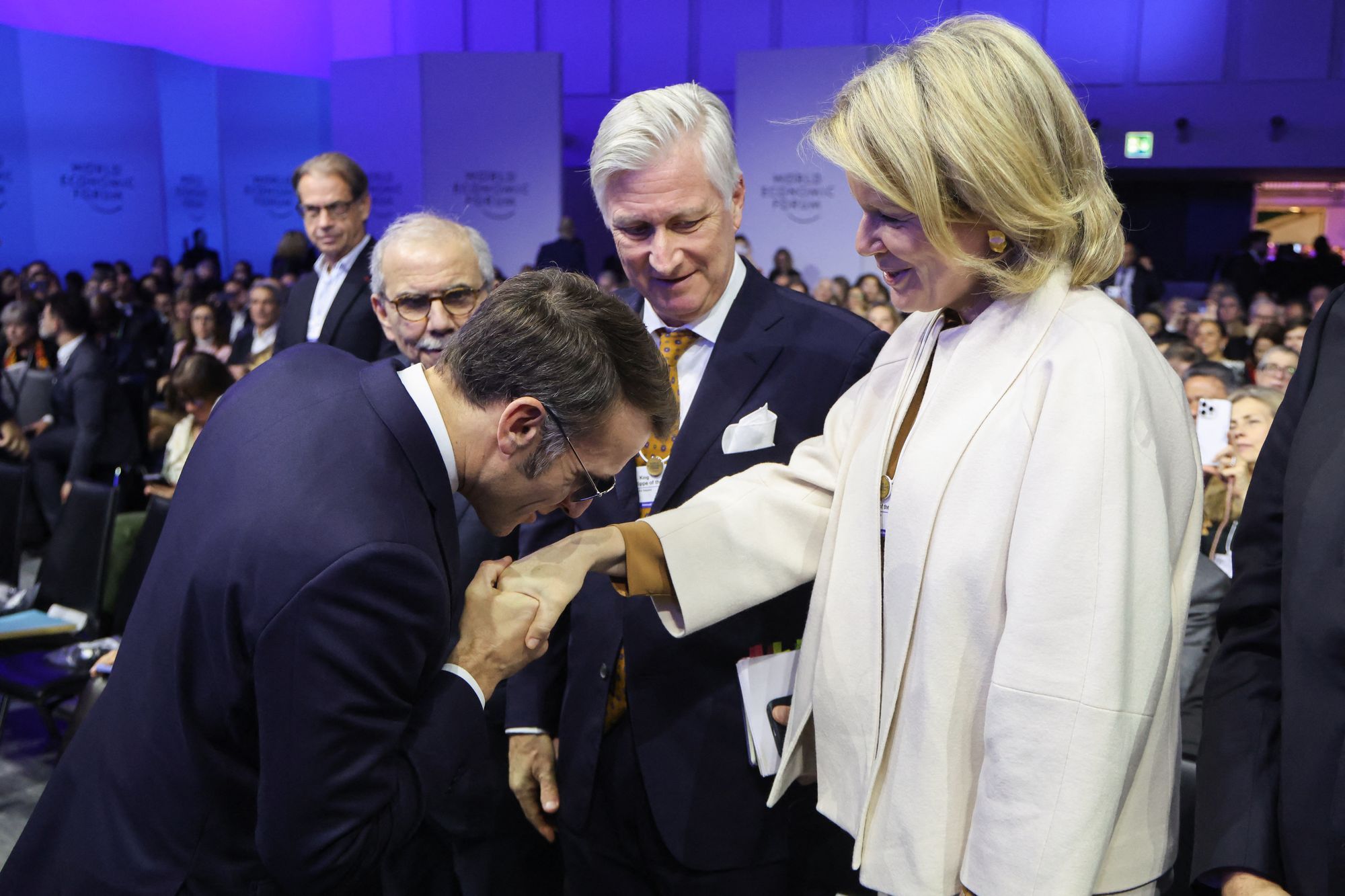 Emmanuel Macron greets Queen Mathilde of Belgium (R) in front of King Philippe