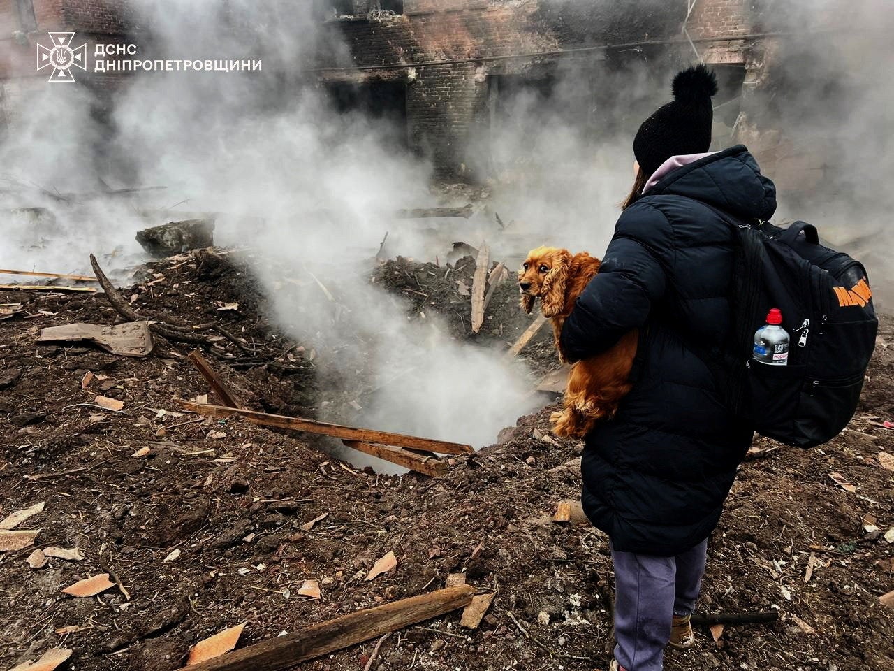 A resident with a dog stands in front of a large crater