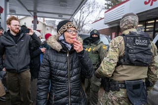 A protester blows a whistle at U.S. Border Patrol agents in Minneapolis Wednesday