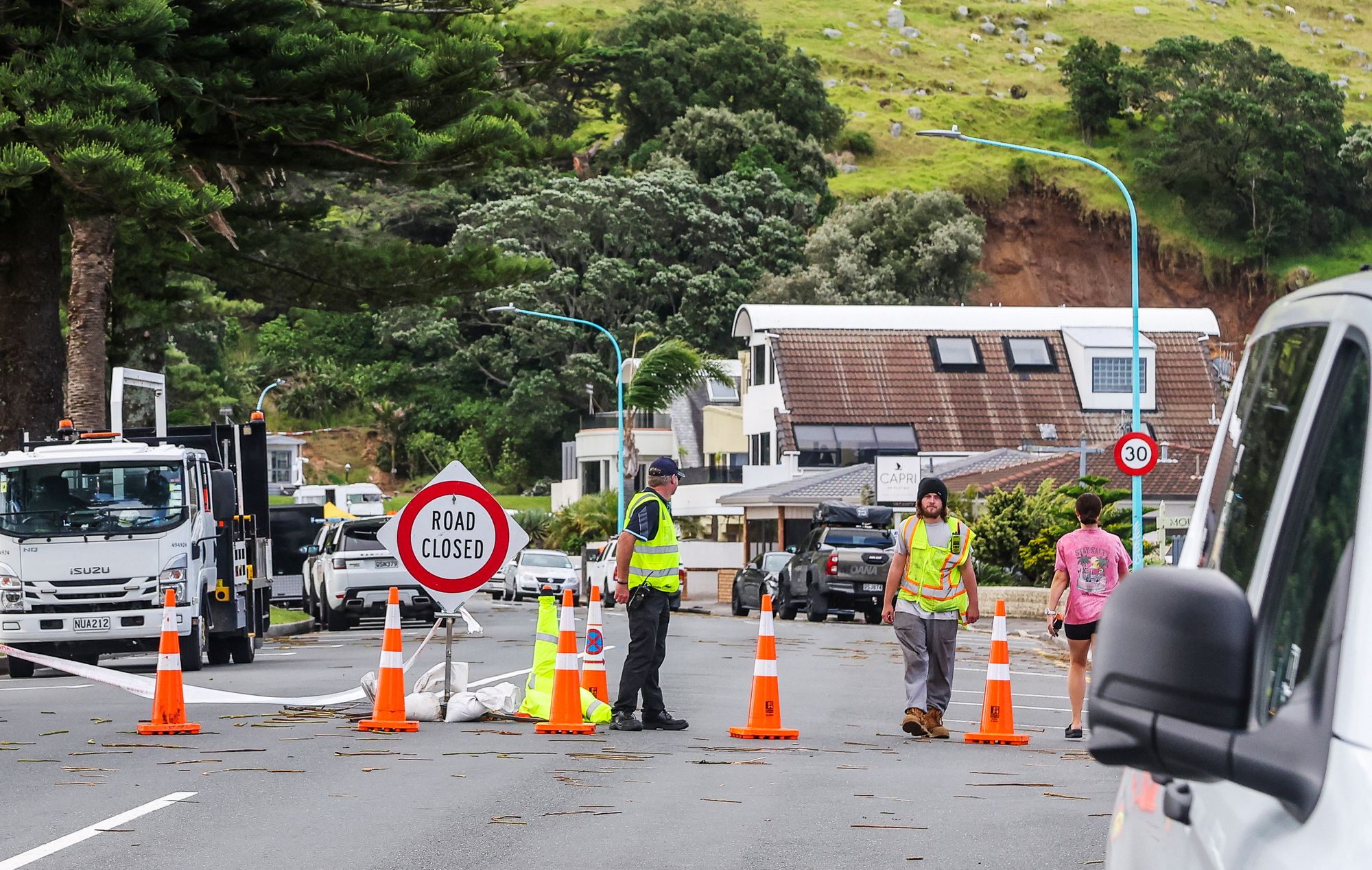 Emergency workers close a road following a landslide while a search is underway by local emergency services for missing people at Mount Maunganui in Tauranga