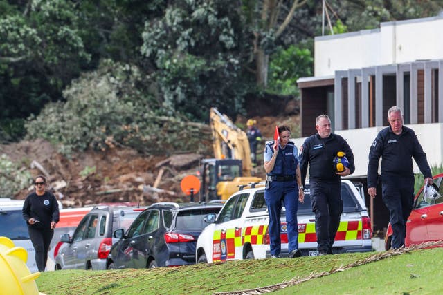 <p>Police and officials walk following a landslide while a search is underway by local emergency services for missing people at Mount Maunganui in Tauranga</p>