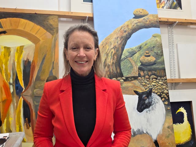 <p>The artist and poet Frieda Hughes stands in front of some of her paintings</p>