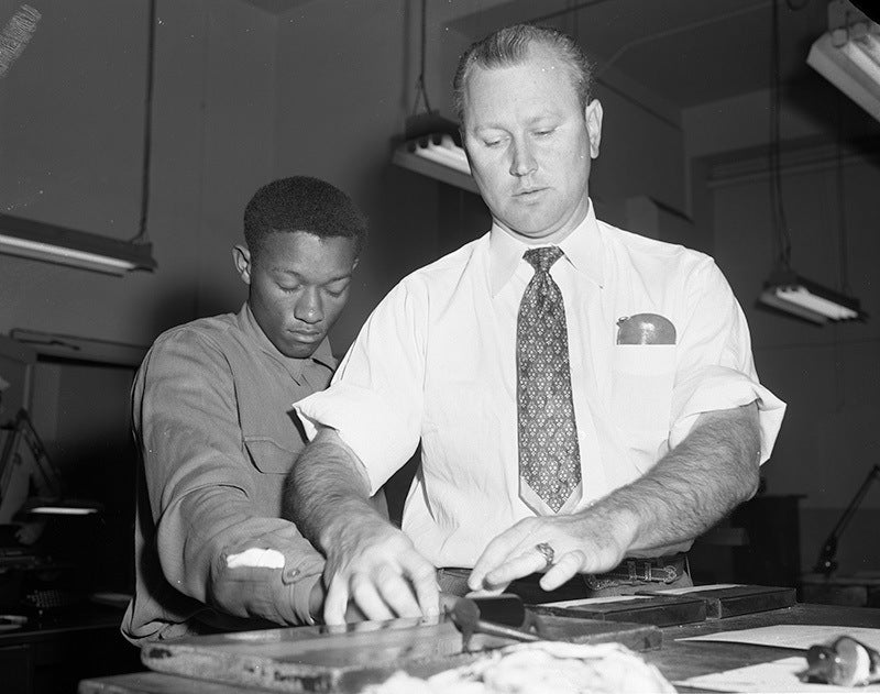 Tommy Lee Walker is fingerprinted after his arrest in January 1954