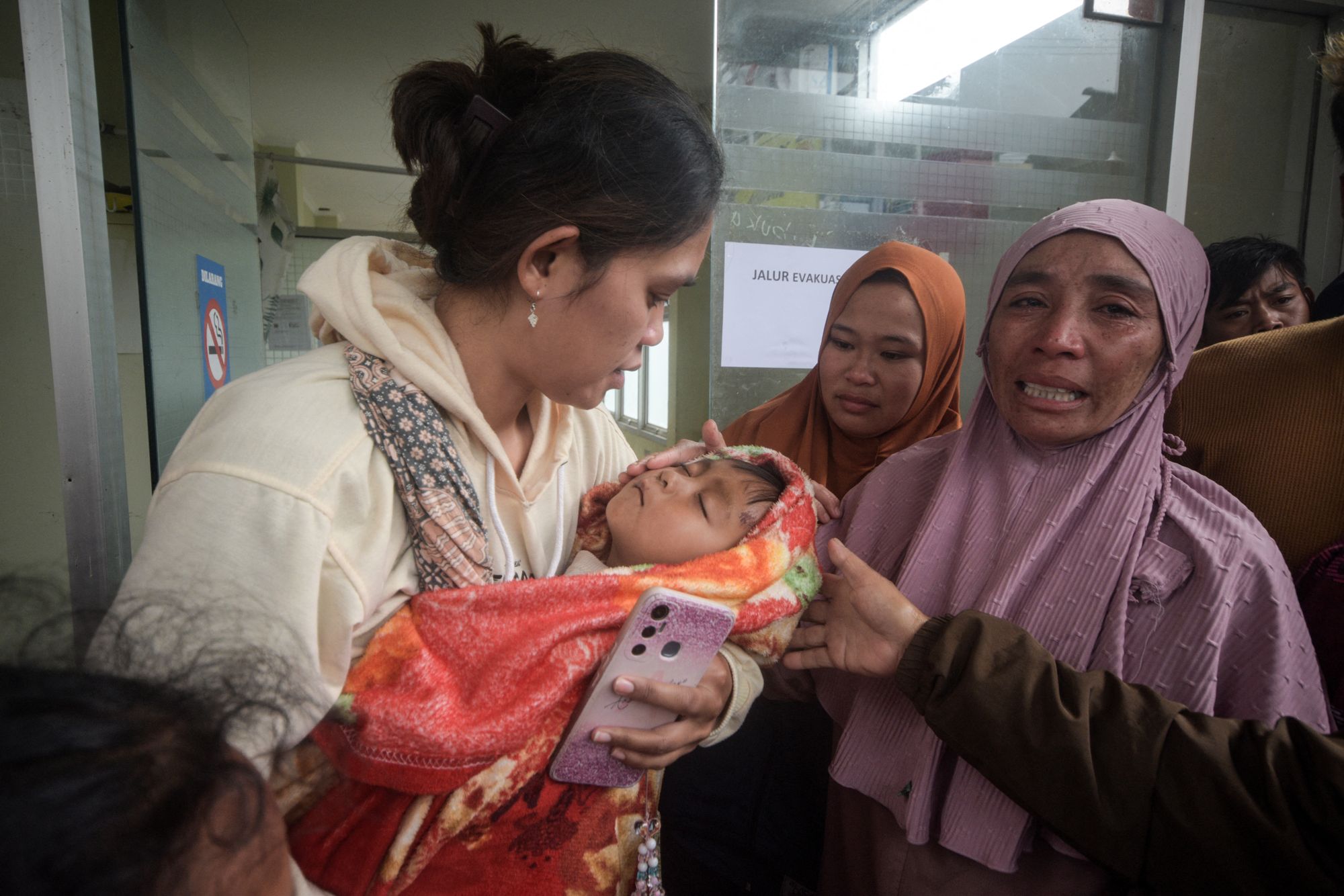 A woman carries a boy who survived a landslide at Pasirlangu village in Bandung, West Java