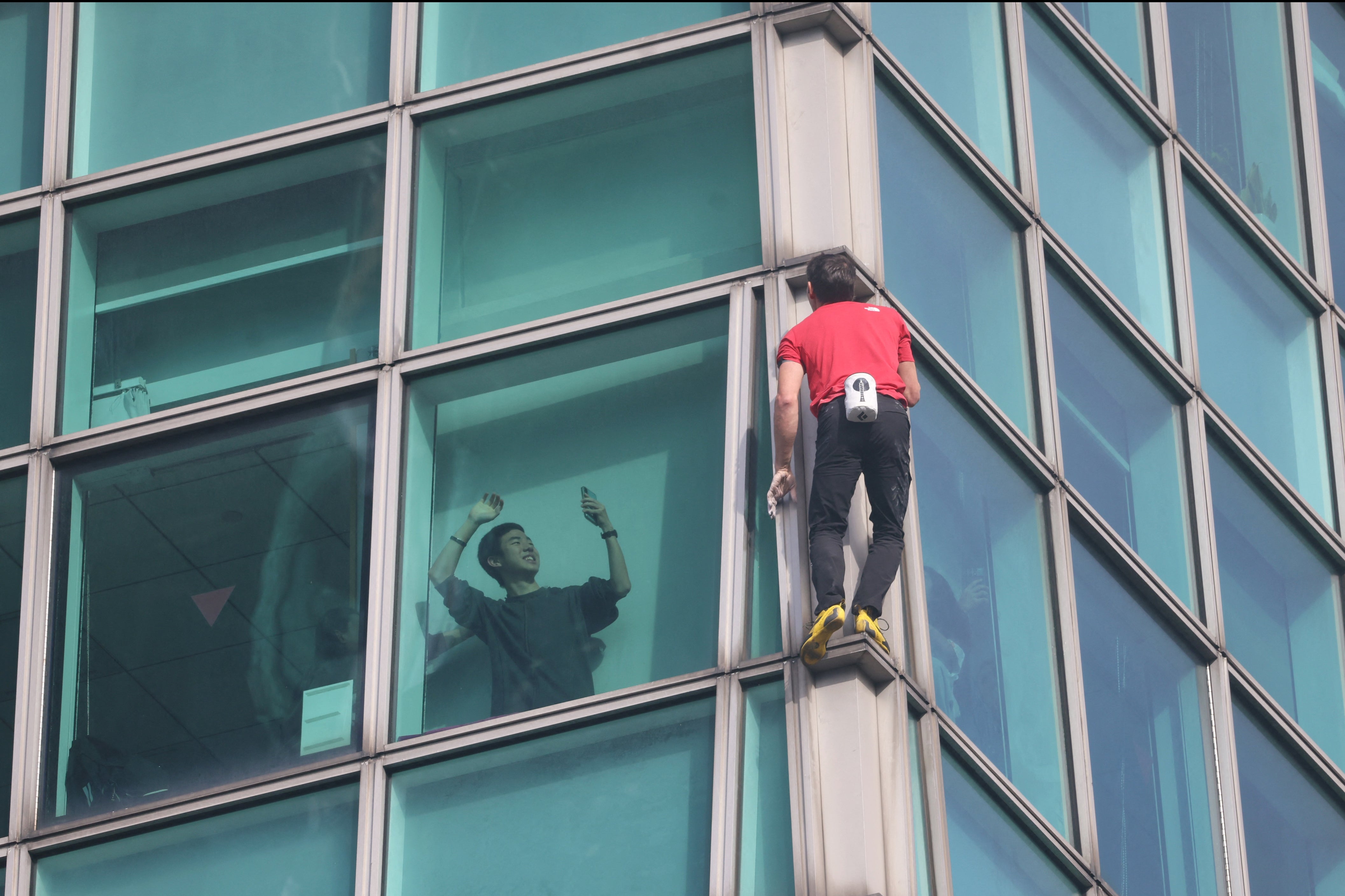 <p>A building occupant uses his phone to record US rock climber Alex Honnold climbing the Taipei 101 building without ropes or safety gear in Taipei on January 25, 2026</p>