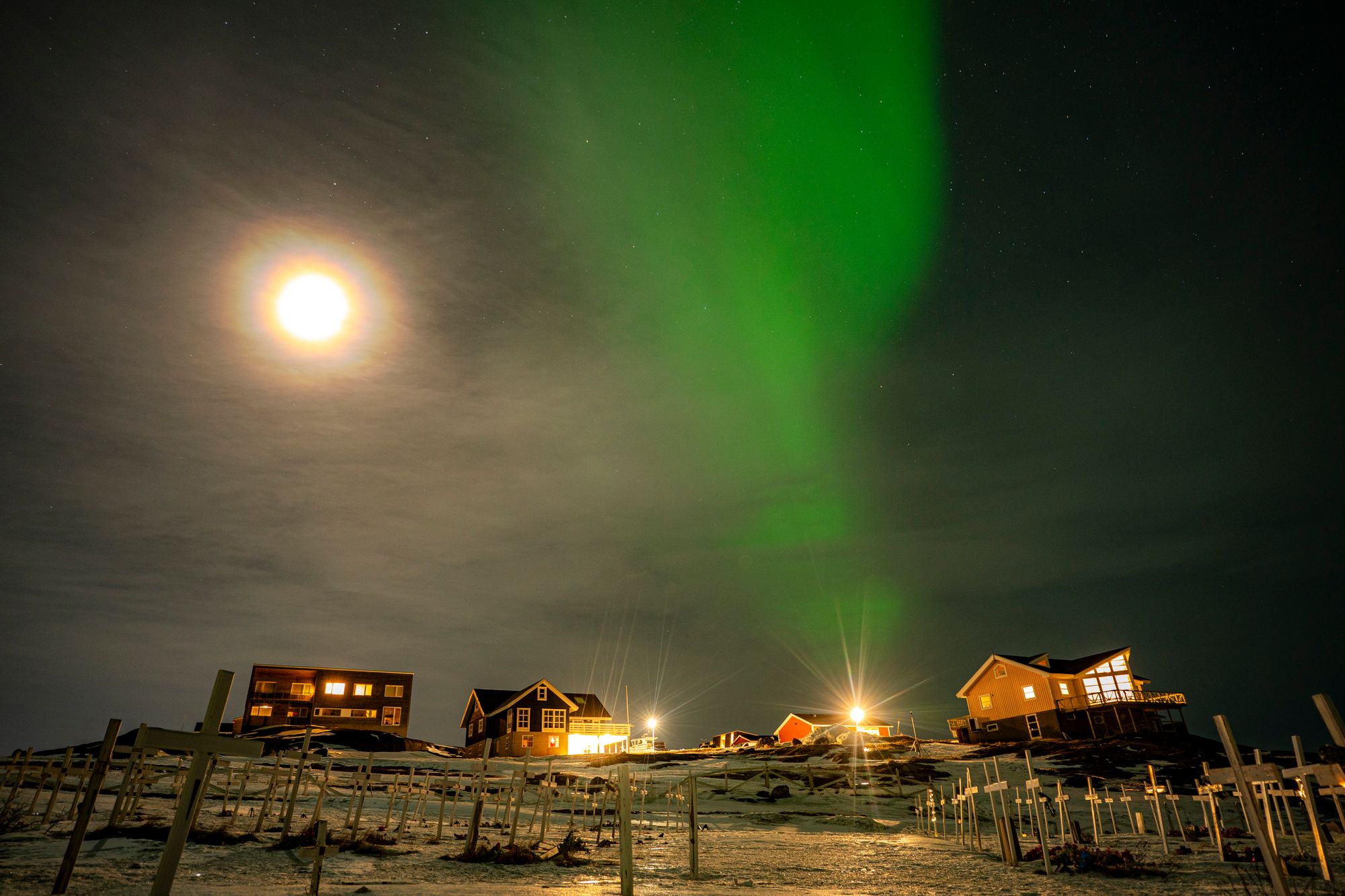 The Aurora Borealis, also known as the Northern Lights, shines over houses and a graveyard in Nuuk, Greenland