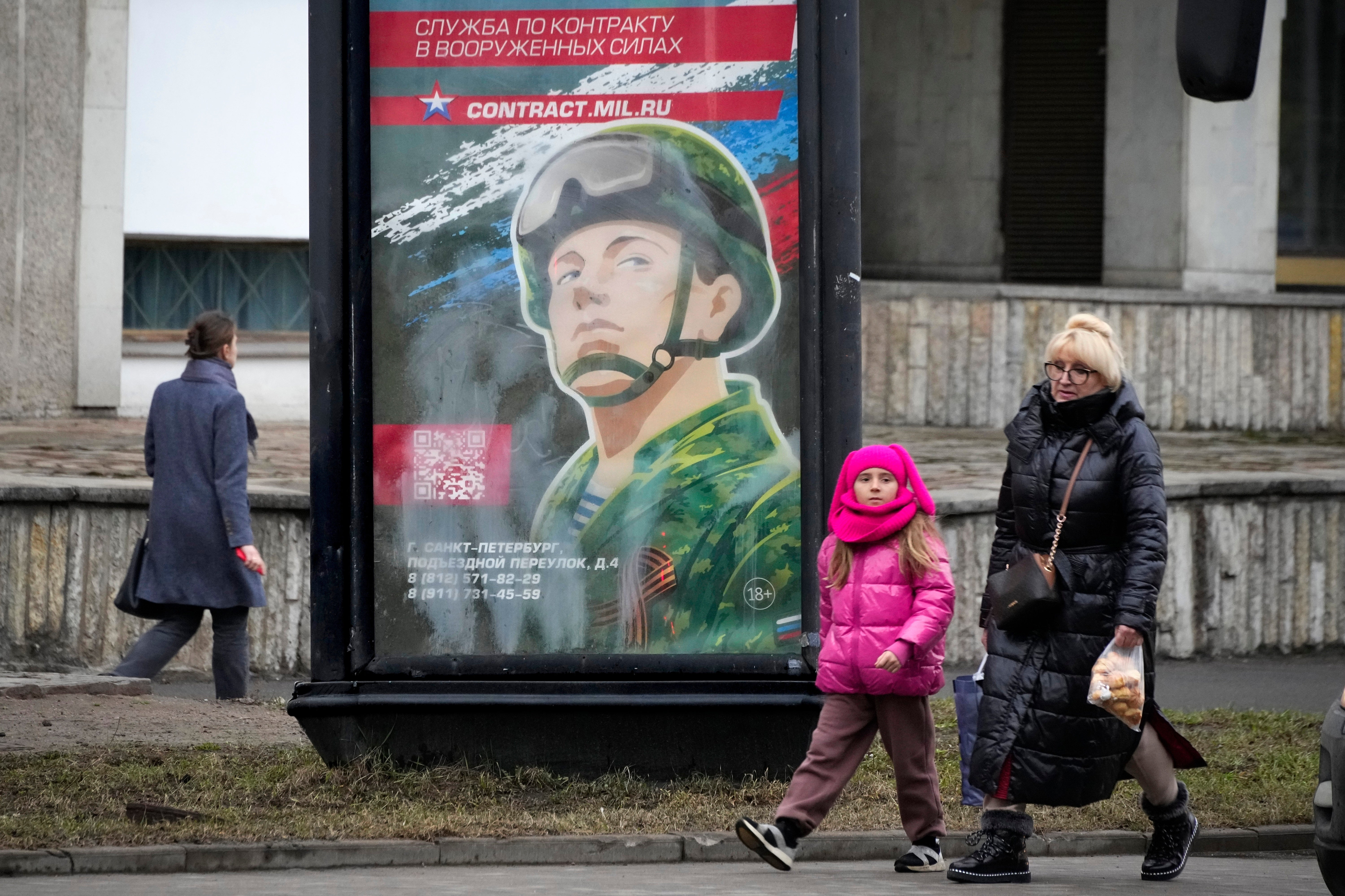 People walk past an army recruiting billboard with the words "Military service under contract in the armed forces," in St. Petersburg, Russia, March 24, 2023. (AP Photo, File)