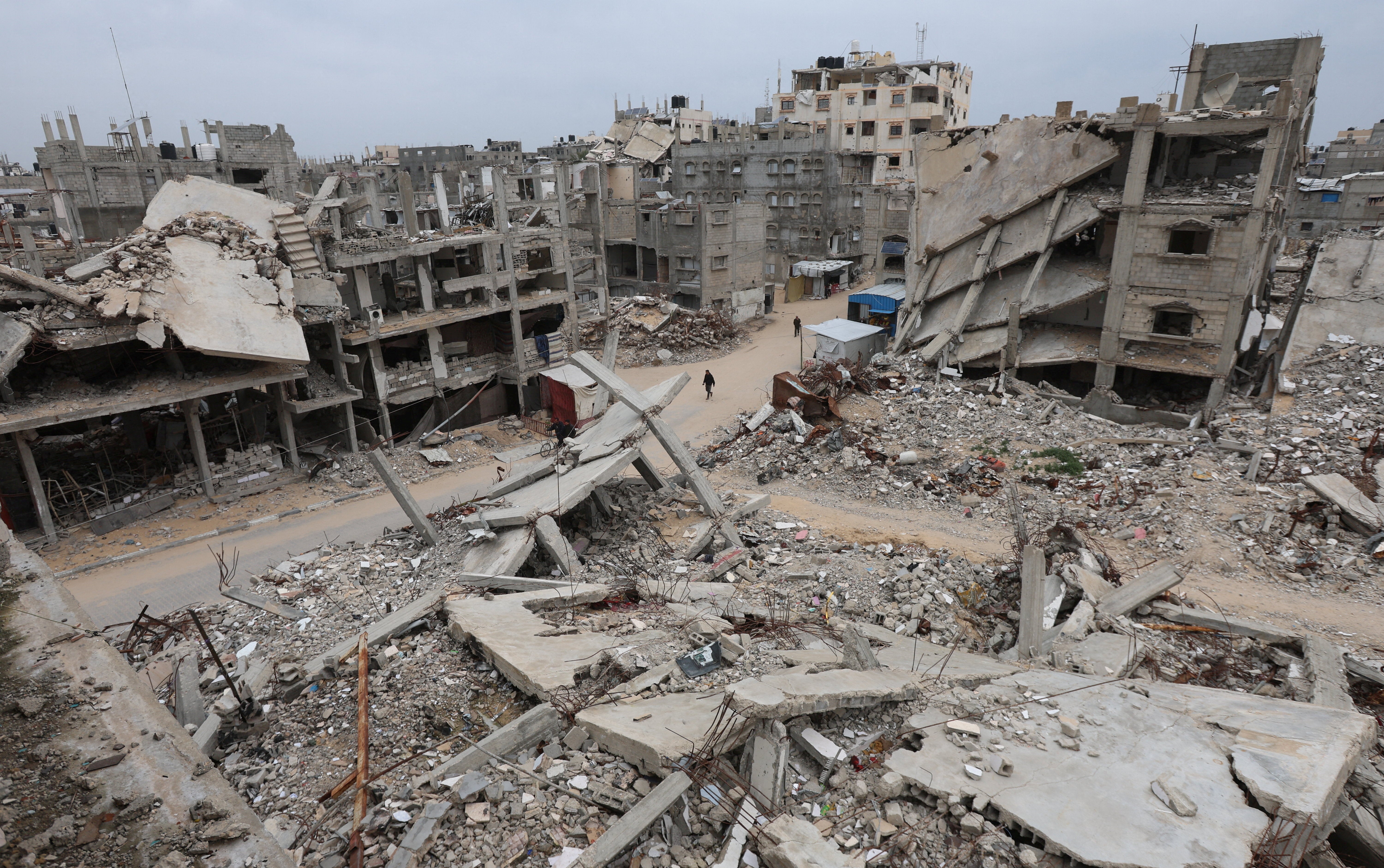 <p>Palestinians walk surrounded by the rubble of houses destroyed in Israeli strikes during the war</p>