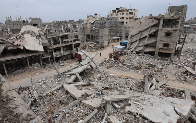 <p>Palestinians walk surrounded by the rubble of houses destroyed in Israeli strikes during the war</p>