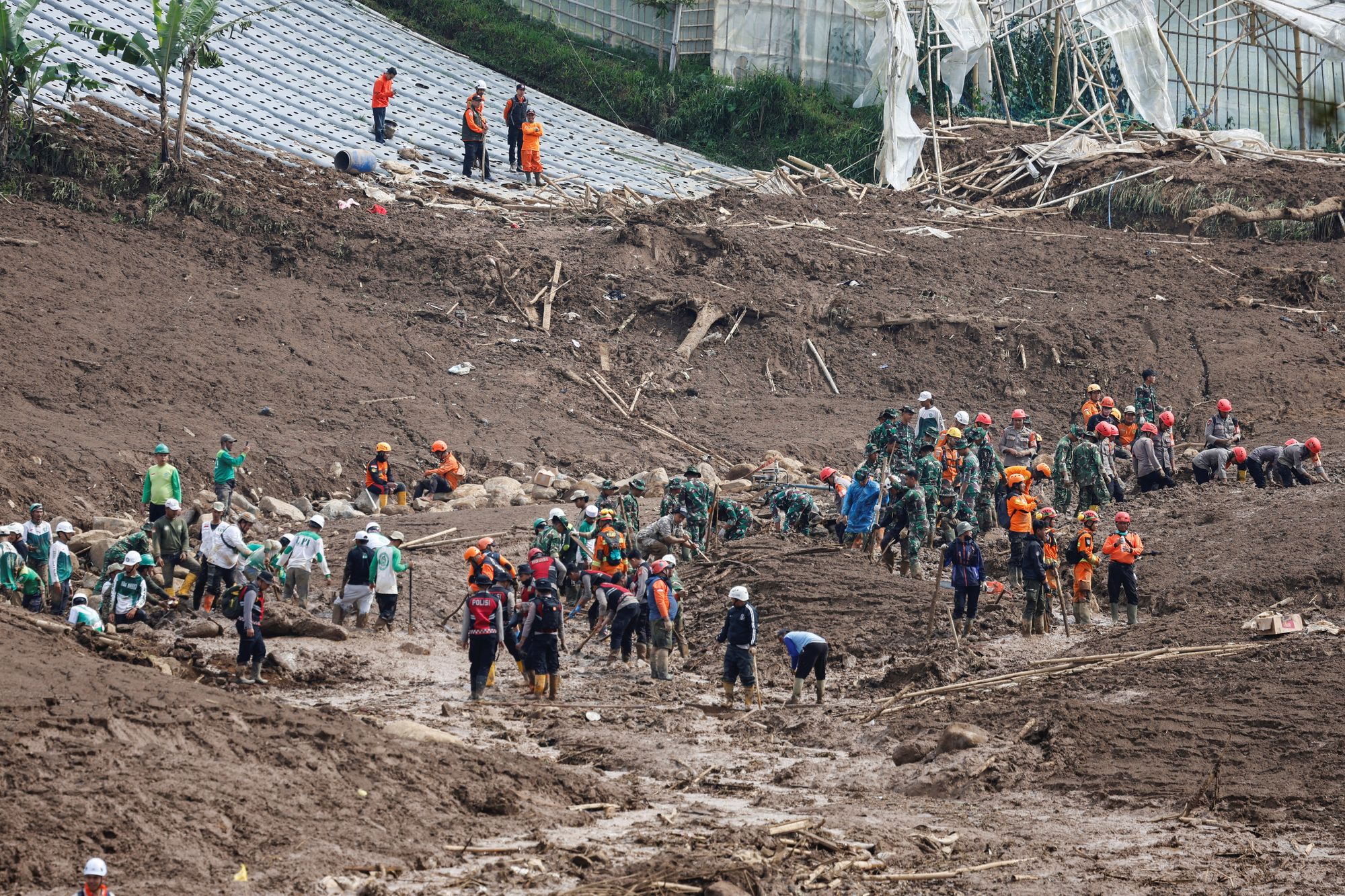 Indonesian rescue members search for victims at the site of a landslide following heavy rains in Pasir Langu village