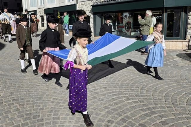 <p>People carry a traditional Ladin flag during a parade through the streets of Cortina D'Ampezzo, northern Italy</p>