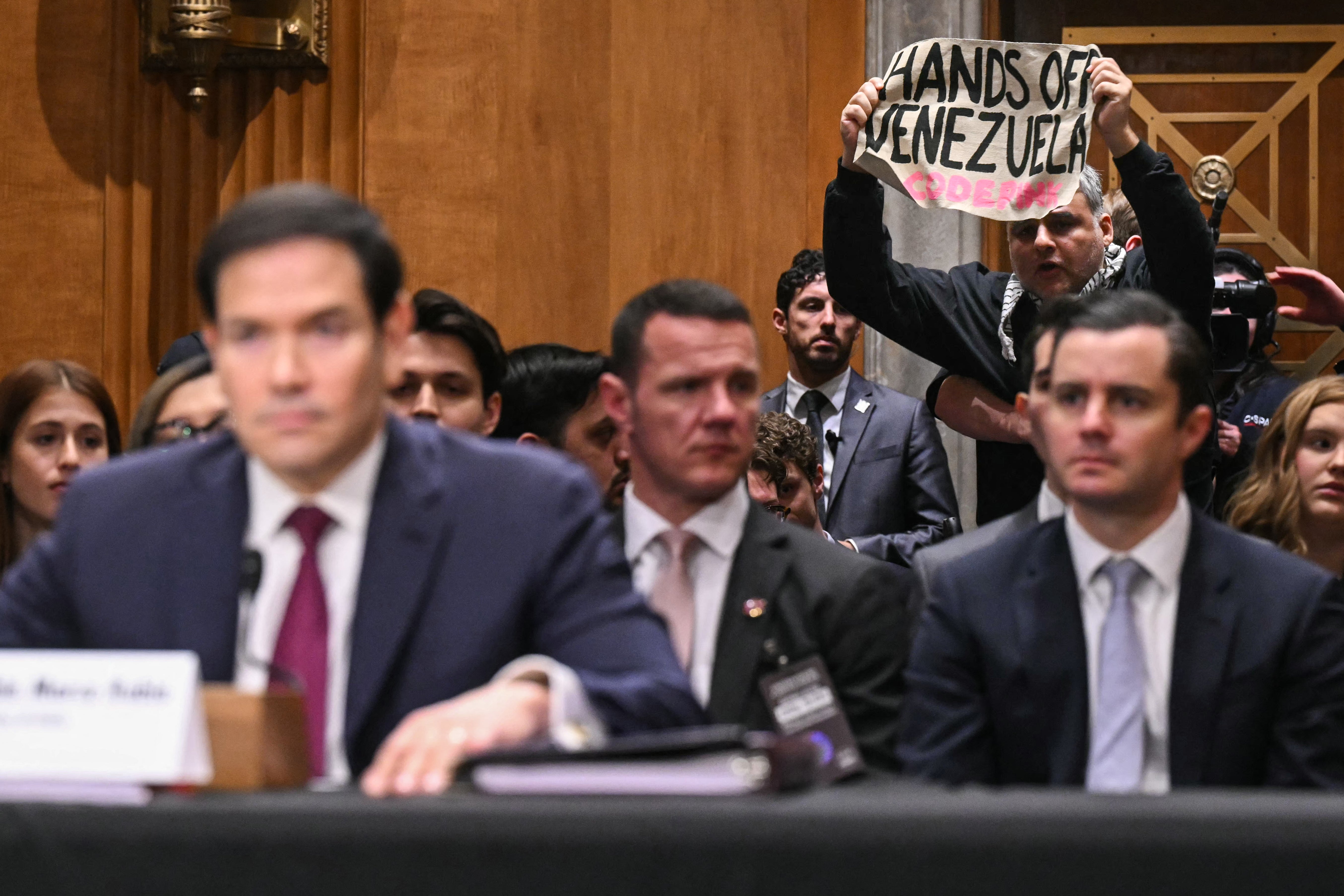 A heckler was quickly removed during opening statements for chanting, ’That’s a war crime. Hands off Venezuela! Hands off Cuba!’