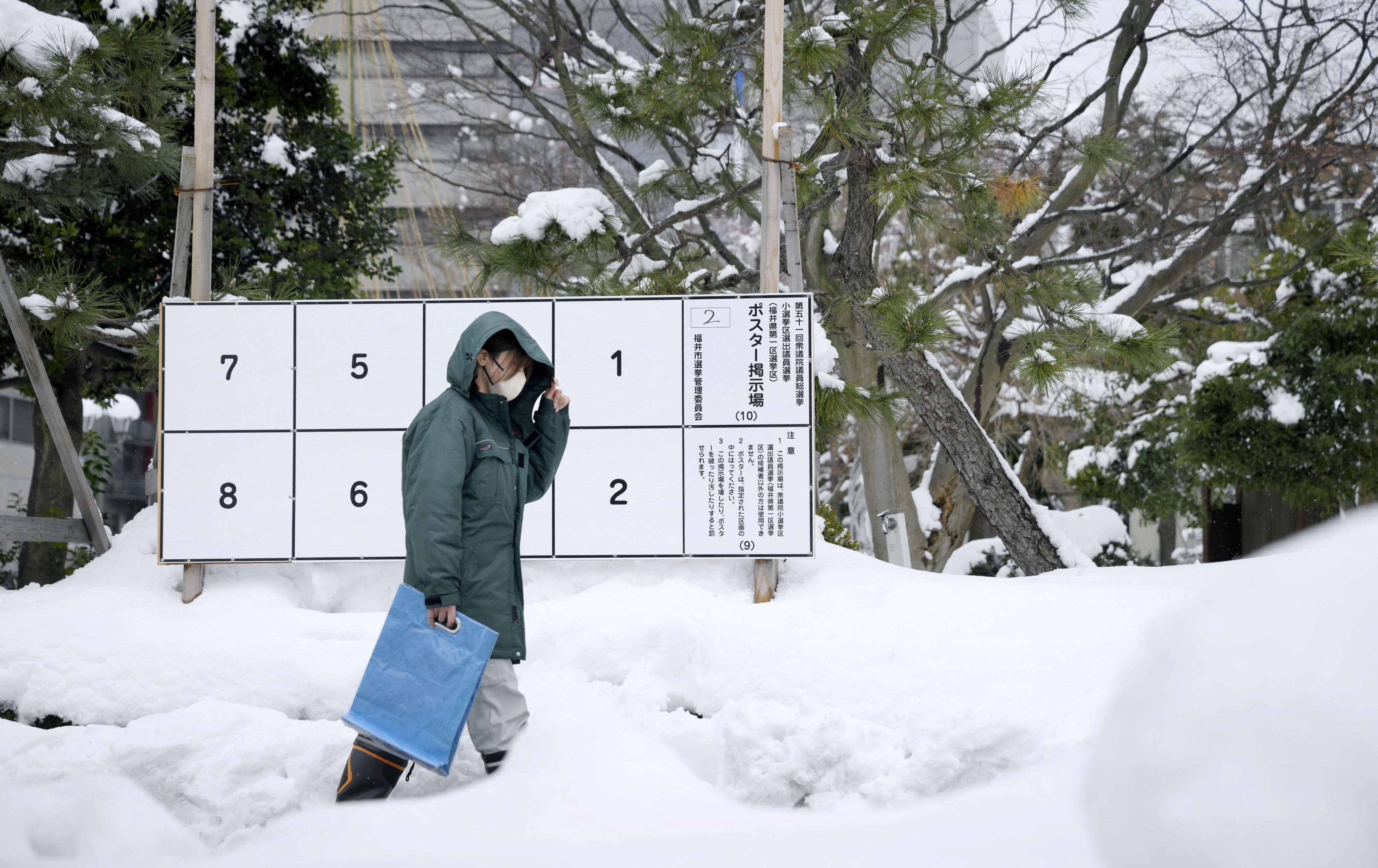 A person walks past a bulletin board for posters of candidates for the February 8 snap election, where snow has accumulated, in Fukui, Japan