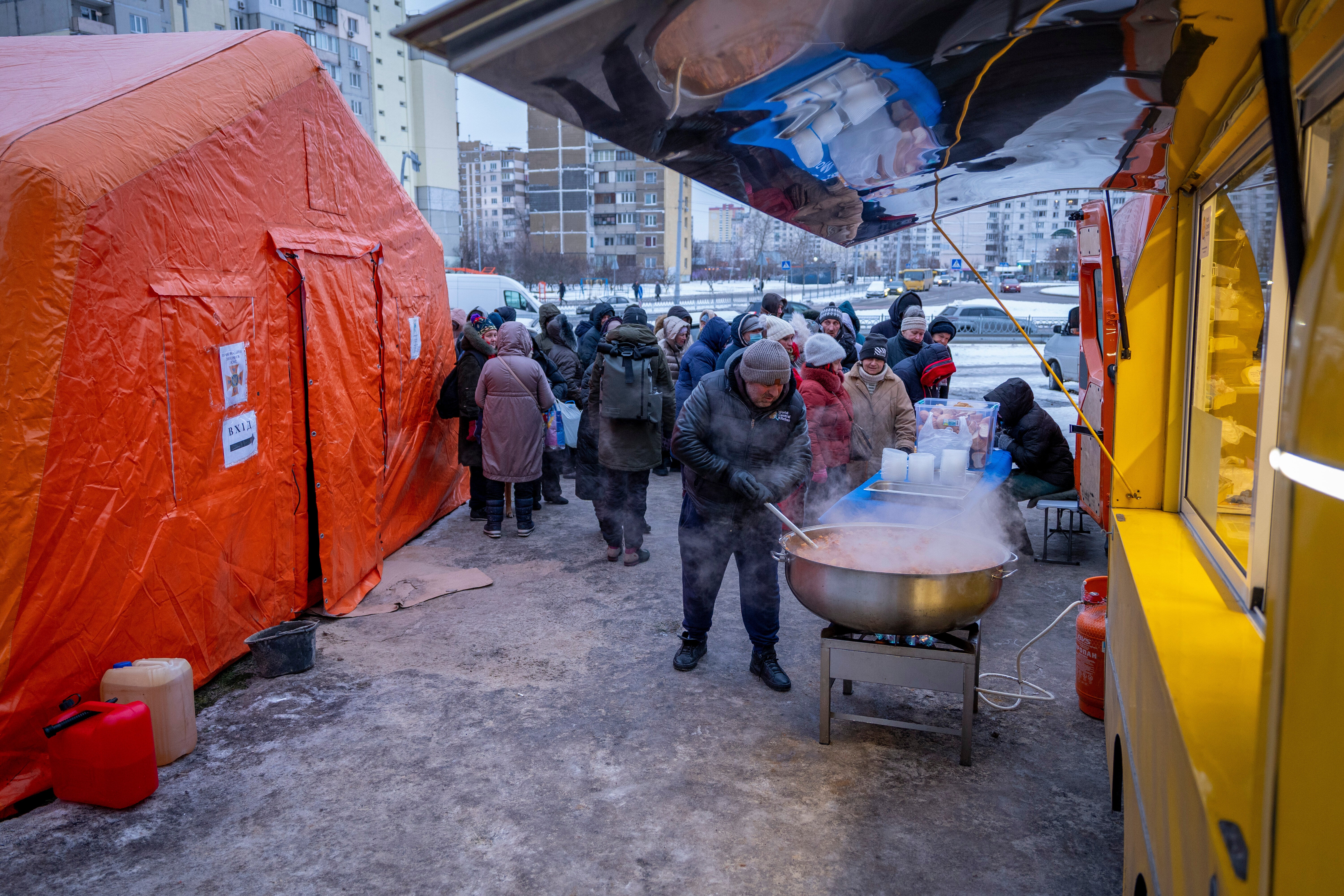 People wait in line to receive free hot meals in a residential neighbourhood in Kyiv