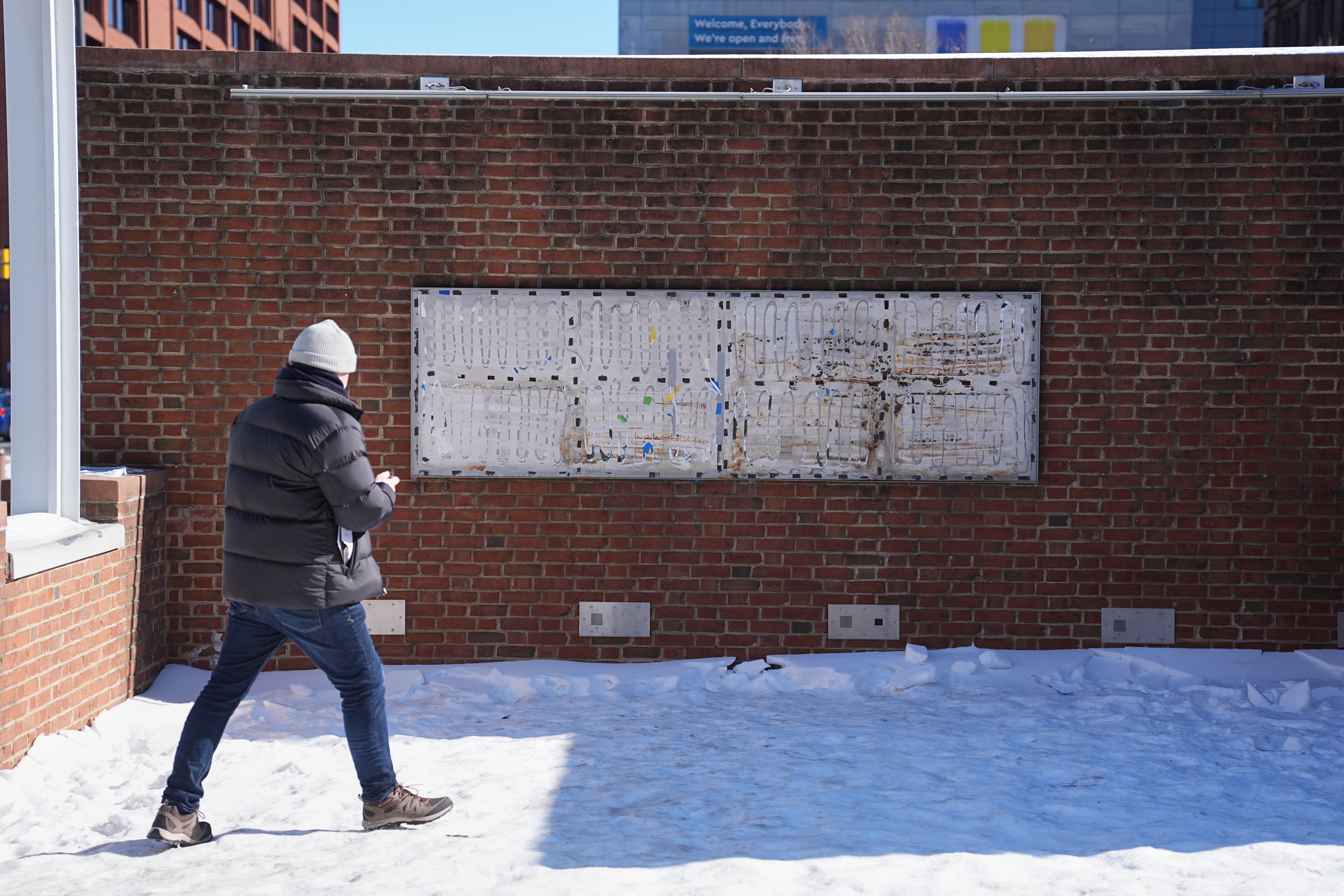 <p>A person moves to photograph the location of the now removed explanatory panels that were part of an exhibit on slavery at President's House Site in Philadelphia</p>