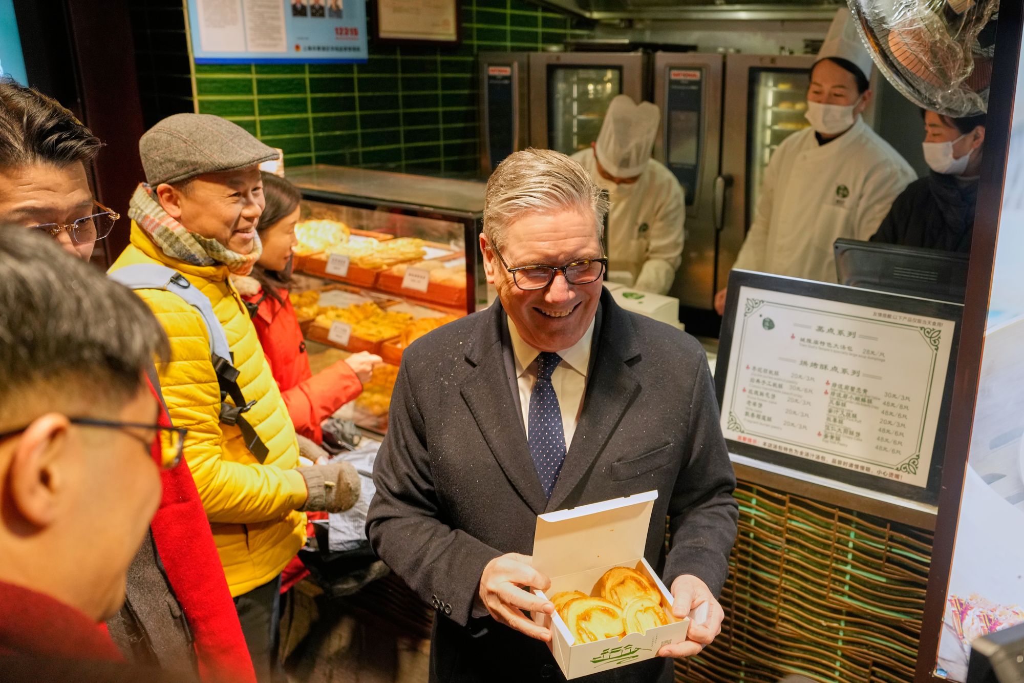 Britain's prime minister Keir Starmer holds up pastry during a visit to Yuyuan Gardens in Shanghai, China, on Friday