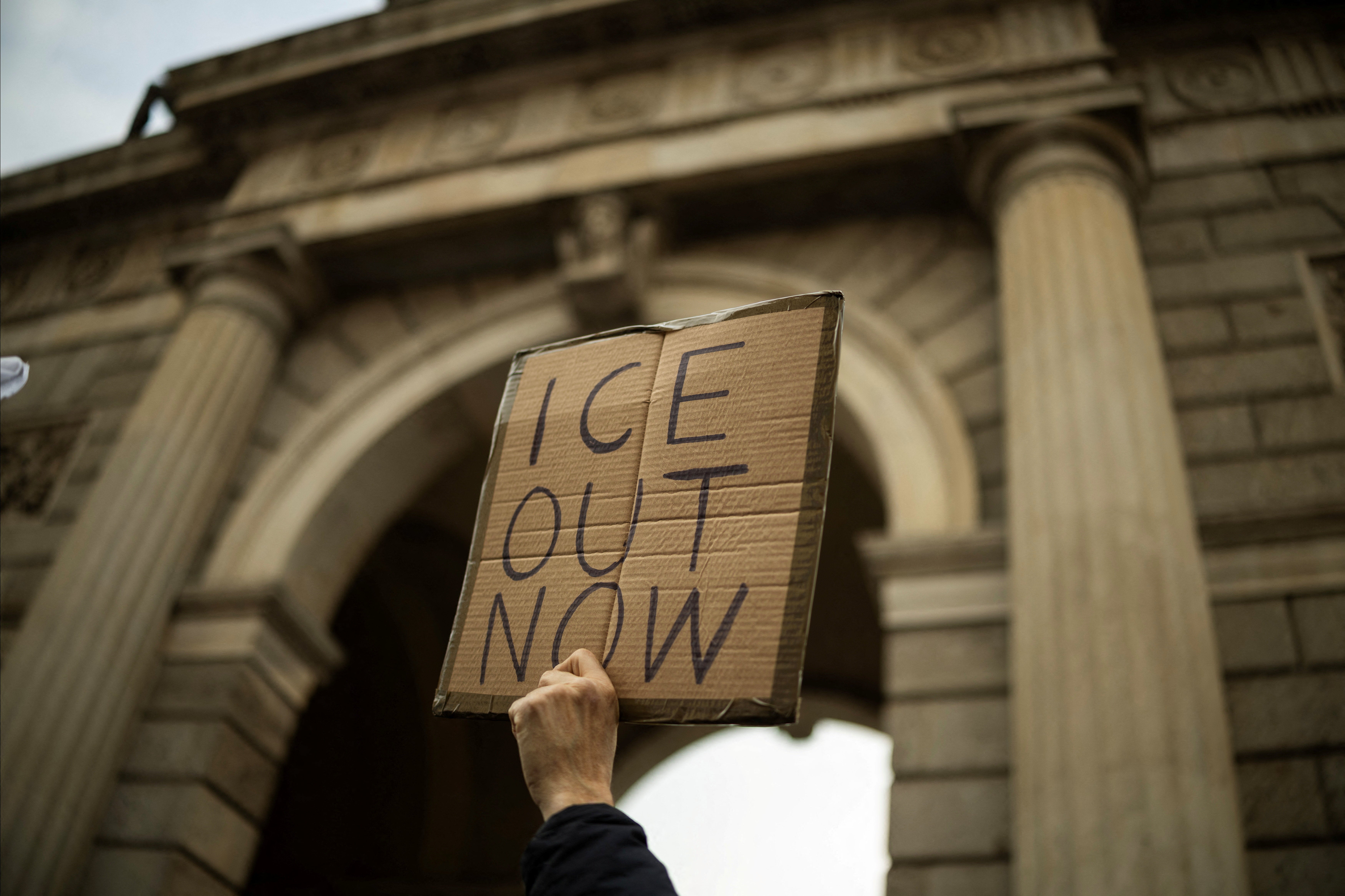 A protester holds a sign saying ‘ICE OUT NOW’